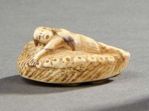 JAPON Netsuké en ivoire sculpté représentant un indigène allongé accroché à un ormeau.
Signature...