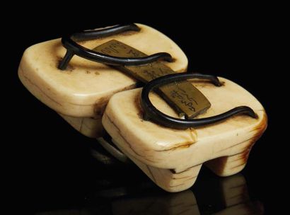 JAPON - XIXE SIÈCLE Netsuke en ivoire en forme de deux geta accolées sur lequel est...