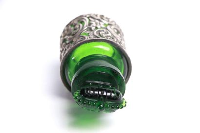 null Green tinted glass bottle in a rococo silver frame.

The cap featuring a closed...