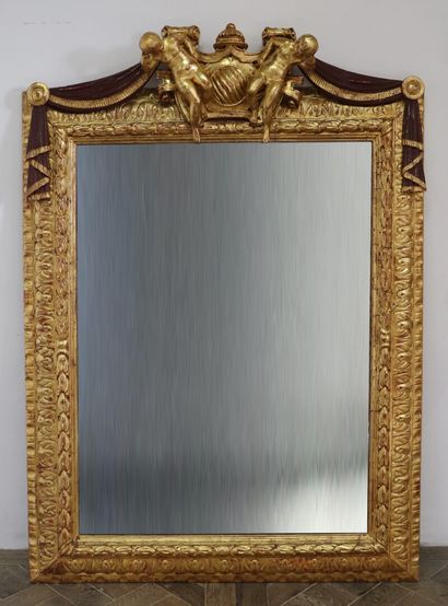null Miroir à fronton en bois et stuc doré, sommé de deux putti encadrant un médaillon...