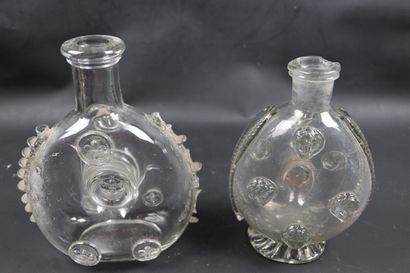 null Two glass bottles, one decorated with faces in application, the other with lily...