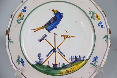 null NEVERS.
Assiette en faïence à décor polychrome d'un oiseau perché sur des outils...