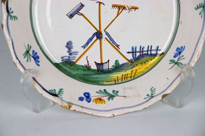null NEVERS.
Earthenware plate with polychrome decoration of a bird perched on tools...