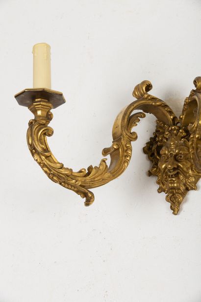 null Suite of four bronze sconces with two lights, the arms supported by a mask of...