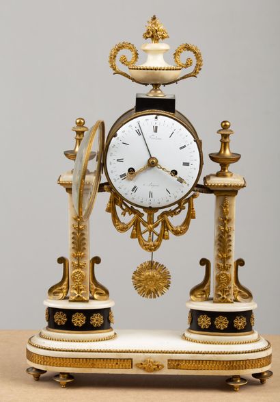 null Portico clock in marble and gilt bronze, topped by a vase with handle.
The dial...