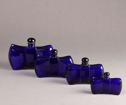 NON VENU (BACCARAT pour GUERLAIN) Suite of four midnight blue glass perfume bottles,...