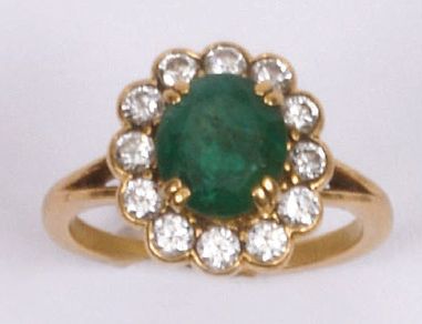 null RING adorned with an oval emerald in a setting of twelve diamonds. Yellow gold...