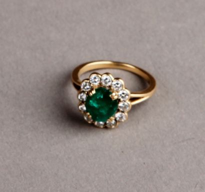 null RING adorned with an oval emerald in a setting of twelve diamonds. Yellow gold...