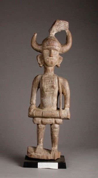 INDE Statue Bastar représentant un personnage debout sur un socle, portant un casque...