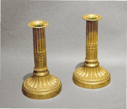 null Paire de bougeoirs en bronze ciselé et doré en forme de colonne cannelée rudentée...