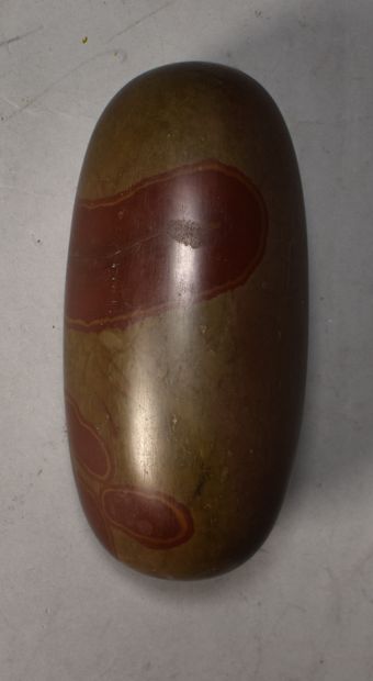 null Cylindrical pebble painted with red patterns. Length 15 cm