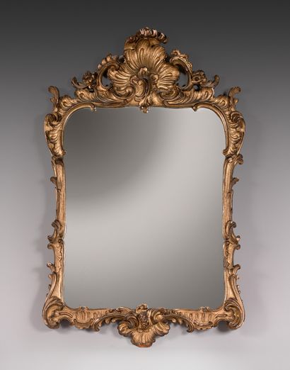 null A pair of carved and gilded wooden mirrors with rocaille and foliage.

Italy,...