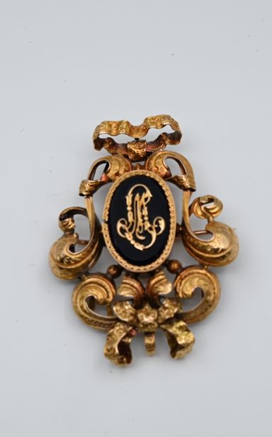 null A yellow gold brooch decorated with knots and scrolls surrounding a medallion...