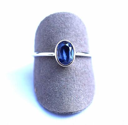 null Bague or blanc centrée en clos d'un saphir ovale probablement Ceylan d'un bleu...