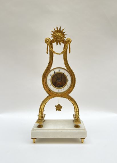null Lyre clock in gilt bronze underlined by friezes of pearls, surmounted by a radiant...
