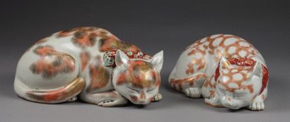 JAPON Deux chats couchés en porcelaine dont un porte un noeud rouge à pois. Décor...