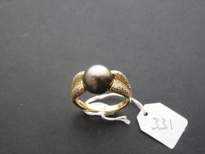 null An 18K (750/oo) yellow gold ring centered on a Tahitian cultured pearl (diameter...