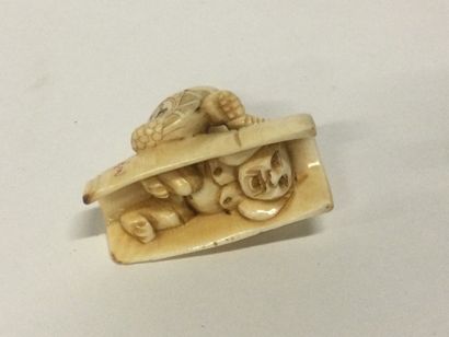 null JAPAN. A carved ivory netsuke representing a character on a barrel hiding an...