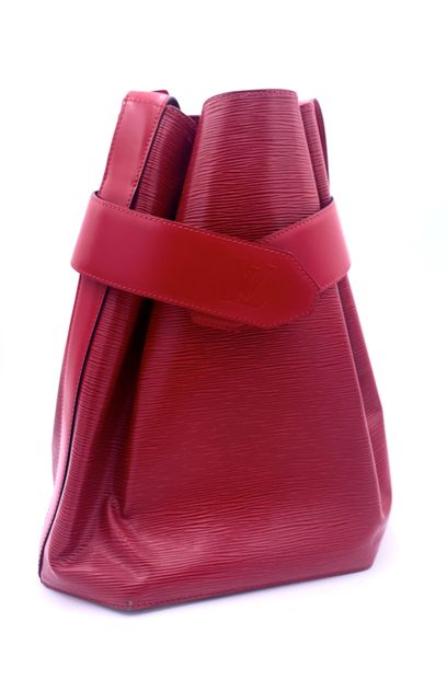 null Louis VUITTON, red leather shoulder bag. Snap closure on wide belt and adjustable...