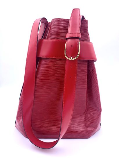 null Louis VUITTON, red leather shoulder bag. Snap closure on wide belt and adjustable...