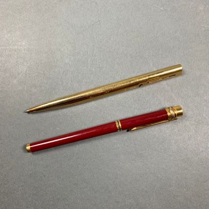 Deux stylos MUST DE CARTIER & BVLGARI Trinity model in gilt metal and red lacquer...