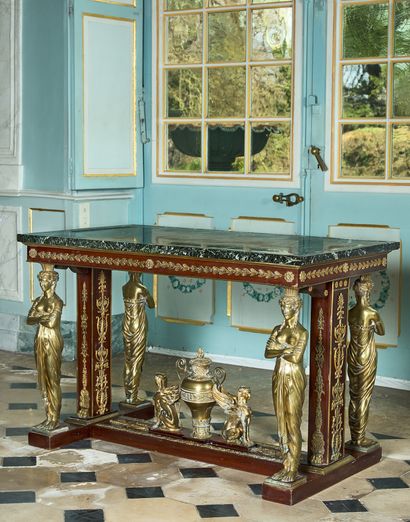  26- Table de milieu en acajou à riche décor de bronzes tels que cariatides, urne...
