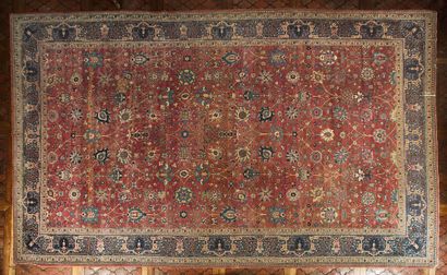  14- Important tapis Persan à décor de fleurs stylisées sur fond rouge. Usures et...