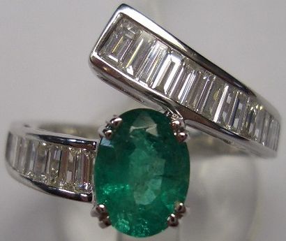 null 117- White gold asymmetrical ring set with an oval emerald and 27 falling baguette-cut...