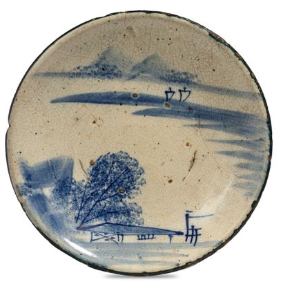 JAPON - XXe siècle Plat en grès émaillé blanc à décor en bleu sous couverte de chaumière...