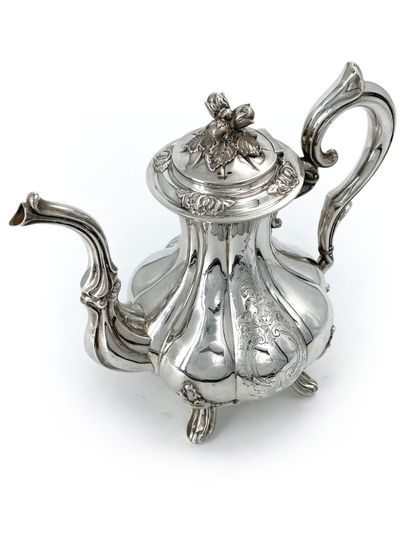 null A large silver teapot with ribs, standing on four feet with twisted rocaille...