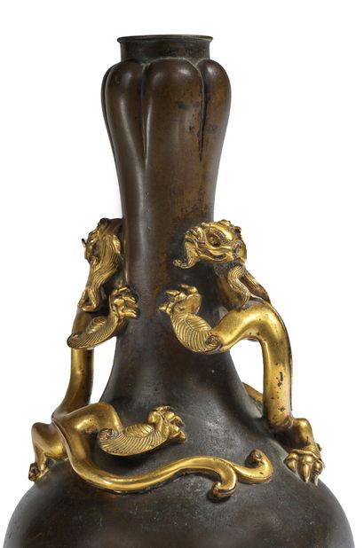 CHINE - Fin Epoque MING (1368 - 1644), XVIIe siècle 
一个特殊的suantouping（大蒜瓣）青铜瓶，带有棕色的铜锈，两只带着双叉尾巴的鎏金青铜盘绕在颈部，并相互对峙。

底座的背面是宣德的天启款，有六个开光的字，略带浮雕和鎏金。

H.23厘米

重量1...