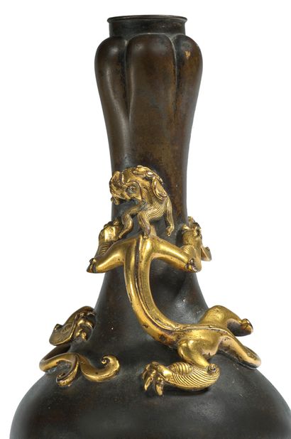 CHINE - Fin Epoque MING (1368 - 1644), XVIIe siècle 
一个特殊的suantouping（大蒜瓣）青铜瓶，带有棕色的铜锈，两只带着双叉尾巴的鎏金青铜盘绕在颈部，并相互对峙。

底座的背面是宣德的天启款，有六个开光的字，略带浮雕和鎏金。

H.23厘米

重量1...