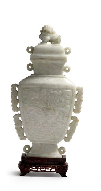 CHINE - XXe siècle 一件白色翡翠覆盖的古式花瓶，两面都雕有古式饕餮和赤龙的面具，把手呈卷轴状。盖子的把手是一个坐着的狮子的形状。木质底座。
H...