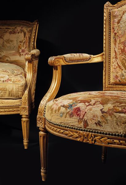 null 雕刻和镀金的木制家具，有扭曲的丝带和花朵装饰，包括一个弯曲的沙发和四个带宪兵帽背的卡布利奥扶手椅。控制台扶手。带凹槽的锥型腿。多色挂毯封面上有人物和动物的场景。
路易十六风格，19世纪末
沙发：高99厘米。宽154厘米。D....
