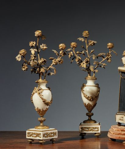 一对白色大理石和鎏金青铜的卵形烛台，三条光臂代表玫瑰花枝。饰以花环、树叶和珍珠网。搁置在一个方形底座上，有小脚。
路易十六风格，19世纪
H.50厘米。L....