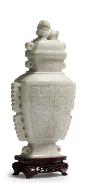 CHINE - XXe siècle 一件白色翡翠覆盖的古式花瓶，两面都雕有古式饕餮和赤龙的面具，把手呈卷轴状。盖子的把手是一个坐着的狮子的形状。木质底座。
H...