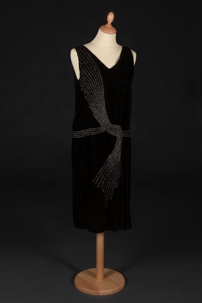Lucien Lelong 黑色天鹅绒无袖连衣裙，尖领，正面绣有水钻，形成一个大结的腰带图案。
1928年春夏
Iconography : L'art et la...
