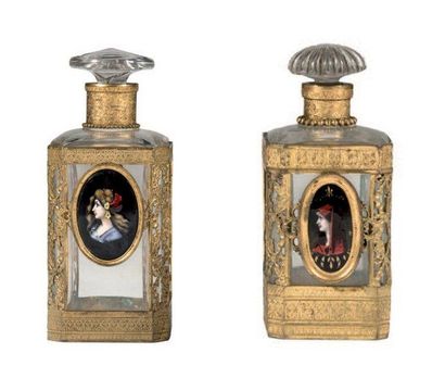 null 两个四角形的玻璃瓶，边上有切口和镀金的黄铜支架；每个中心都有一个多色珐琅的金属奖章，代表一个女性的轮廓。19世纪晚期。高23厘米和13厘米（*）。
