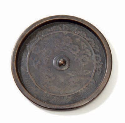 JAPON Miroir en bronze à décor moulé de grues parmi les fleurs.
Diam. 11 cm.