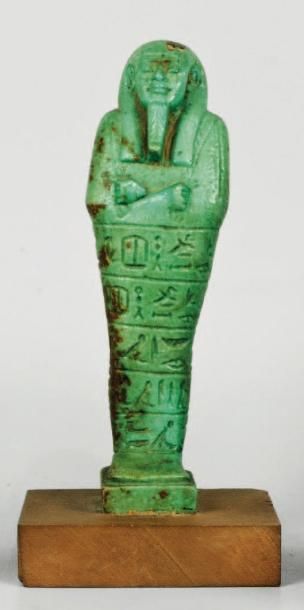 EGYPTE Shaouabti en céramique émaillée verte, anépigraphe, longiligne. Il tient les...