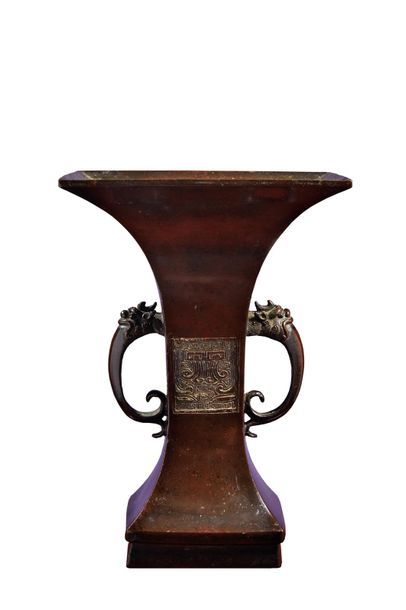 JAPON Vase de forme gu en bronze à pa­tine brune, le corps orné de masques de taotie,...