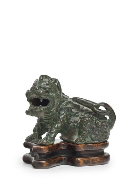 CHINE Statuette de qilin en bronze à patine verte assise, la tête tournée légèrement...