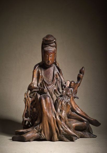 CHINE - XVIIIe siècle Statuette of Guanyin in carved root, sitting on a base holding...