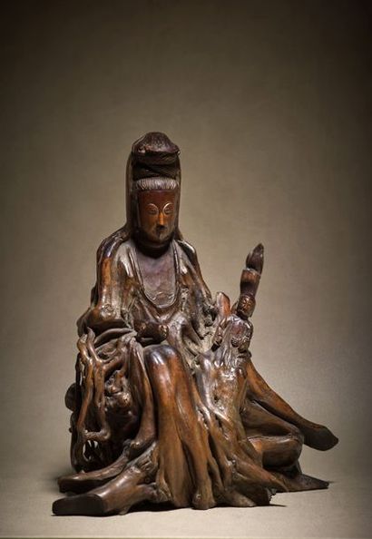 CHINE - XVIIIe siècle Statuette of Guanyin in carved root, sitting on a base holding...