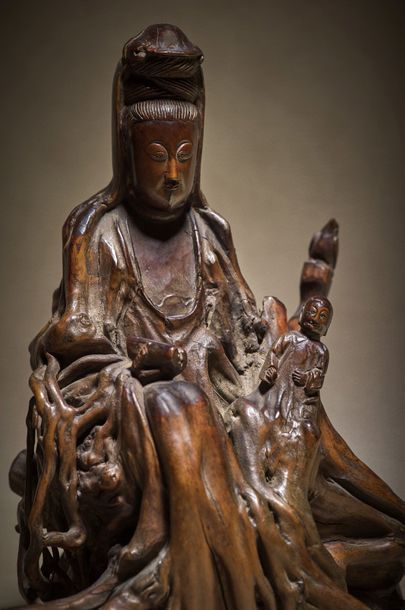 CHINE - XVIIIe siècle Statuette of Guanyin in carved root, sitting on a base holding...
