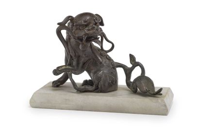 CHINE - XIXe siècle A bronze sitting chair, holding a branch in its mouth and turning...