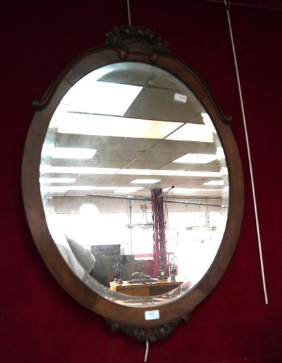 null 
Miroir ovale biseauté, encadrement en bois plaqué, sculpté d'un panier de ...