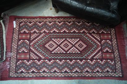 null Trois petits tapis en laine à fond rouge et décor géométrique et un kilim.