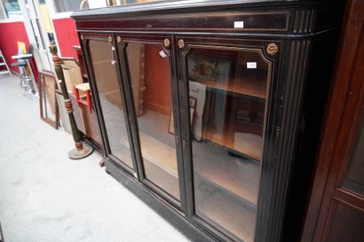 null Importante vitrine en bois noirci et filets de laiton ouvrant par trois portes...