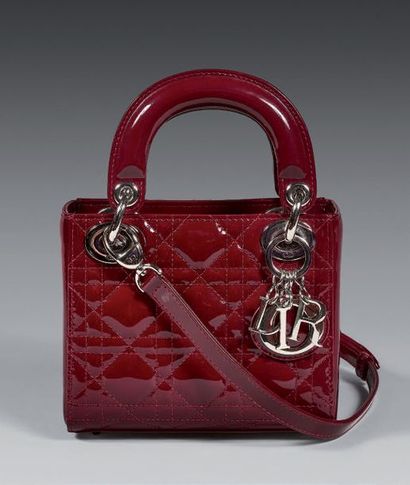 CHRISTIAN DIOR SAC " LADY DIOR " mini 17cm.
Cuir verni bordeaux à surpiqûres cannage,...